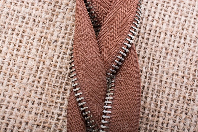Parts of the brown color zipper on linen canvas background