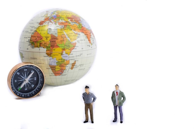 A couple by the side of a globe with a compass on isolated white background