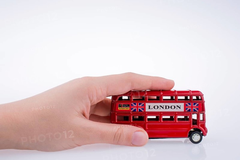 Child hand playing with London double decker bus model on white background