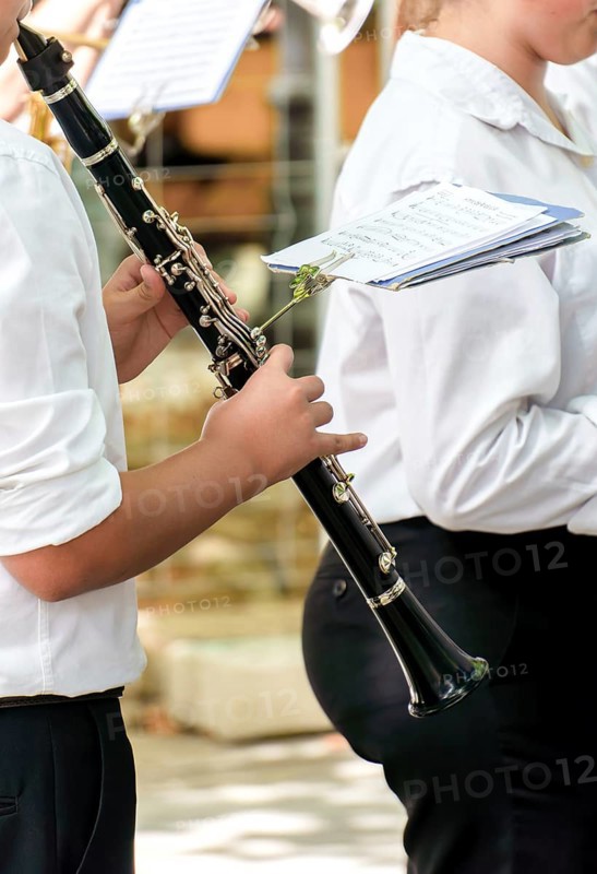 Woman's hands playing a clarinet with sheet music in the background