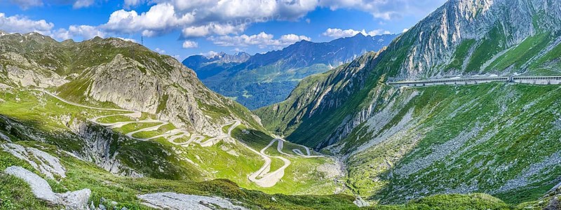 PanoramafoView of old southern pass road Tremola south ramp with serpentines narrow hairpin bends on steep mountain slope of Gotthard Pass on left