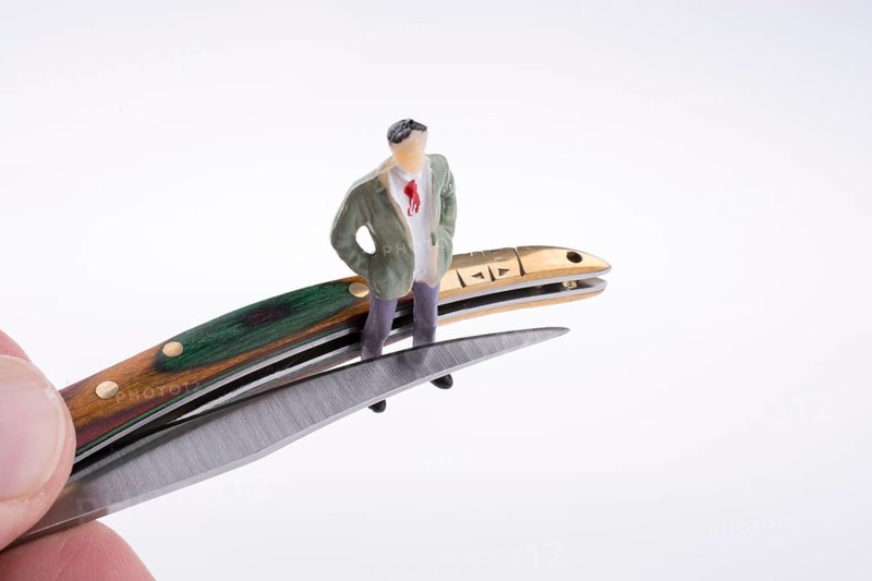 Hand holding a pocket knife near a human figure on a white background