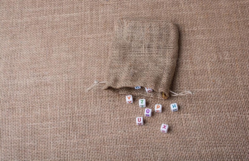 Colorful alphabet letter cubes out of sack on a canvas
