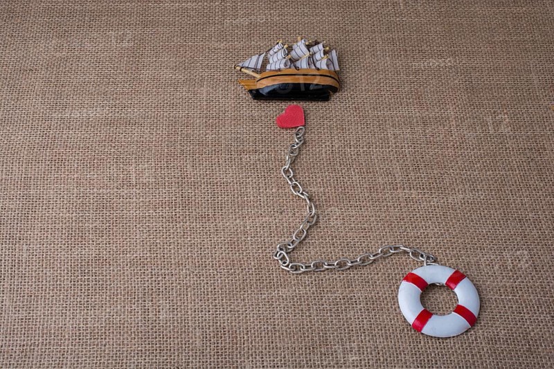 Heart attached to a life preserver and a sail boat
