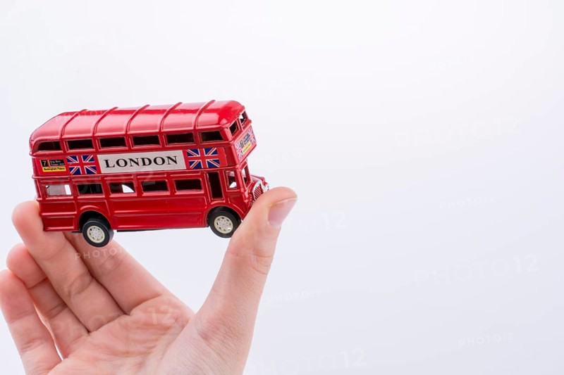 Hand holding a London double decker bus on a white background