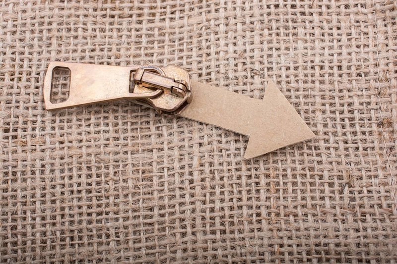 Arrow sign cut out of paper with zipper on canvas