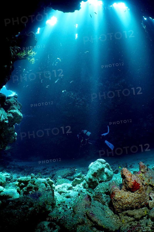 Diver swimming in cave