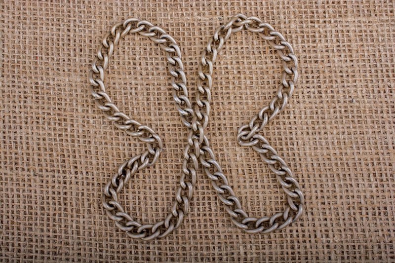 Chain formes a butterfly figure on a linen canvas