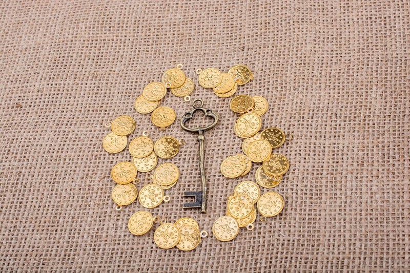 Hand holding a retro styled key over fake gold coins