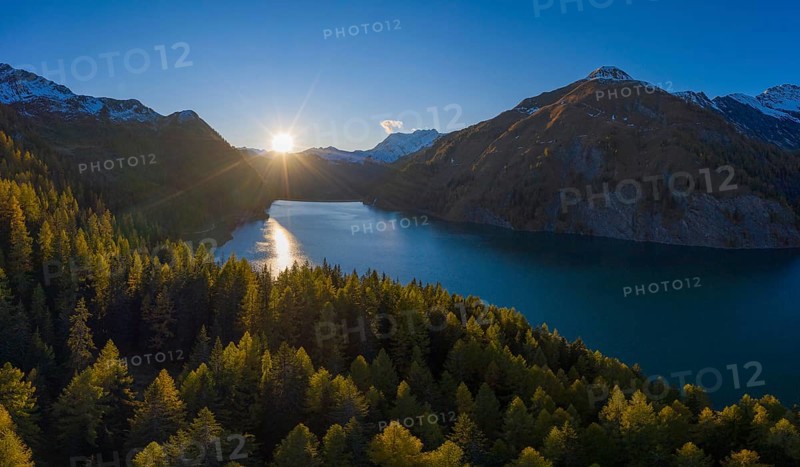 Aerial view at sunset over the autumnal forest at Lago di Luzzone in Valle di Blenio