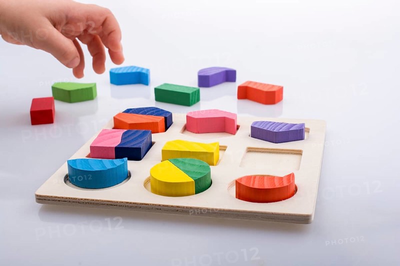 Colorful wooden pieces of a logic puzzle in hand
