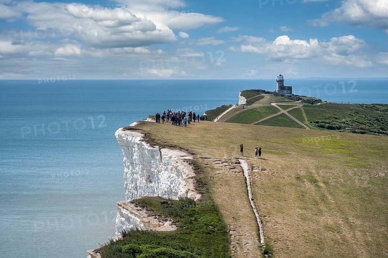 Tourists walking along the chalk cliffs at Beachy Head