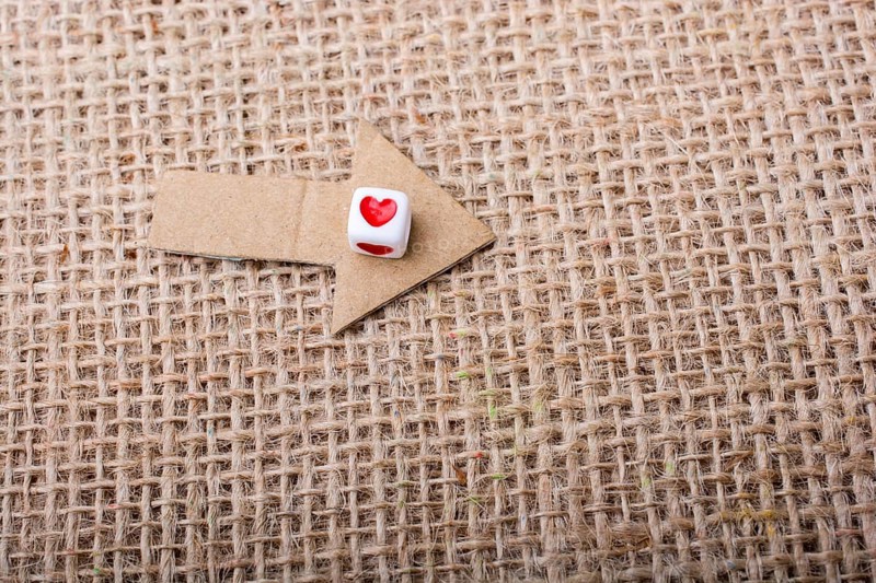 Love cubes on arrow cut out of brown paper on canvas