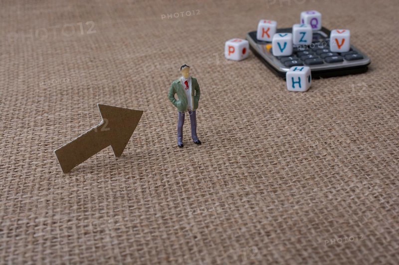 Colorful letter cubes and a calculator beside a figurine