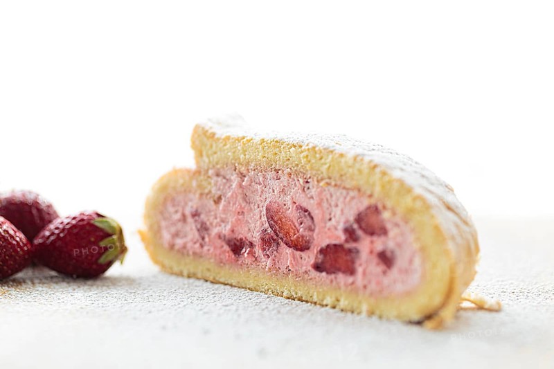 Delicious fruity sponge roll with strawberry filling Strawberry Quark Sponge Roll sprinkled with icing sugar
