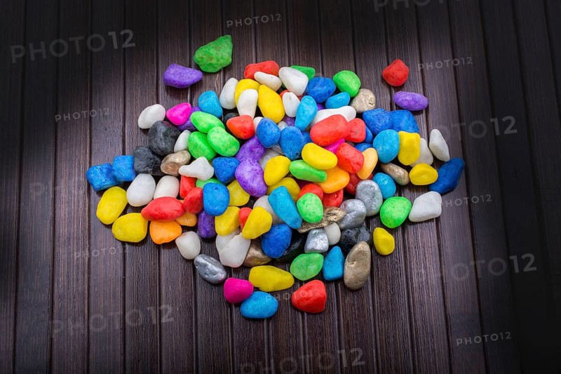 Pile of little colorful pebbles on wooden background
