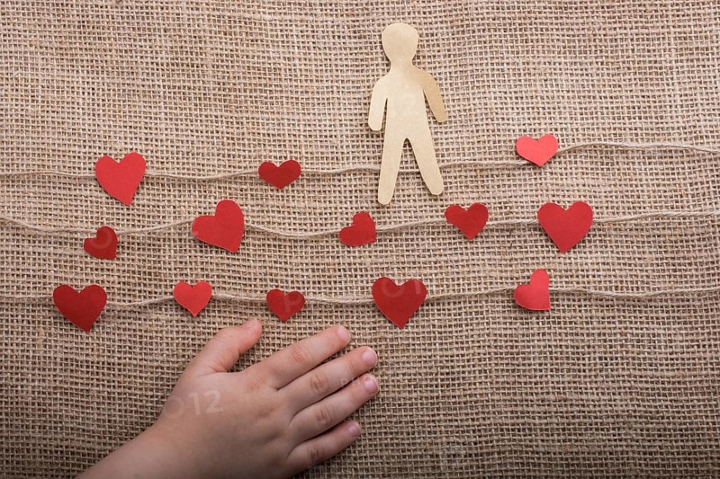 Paper man and heart icons on linen threads on canvas