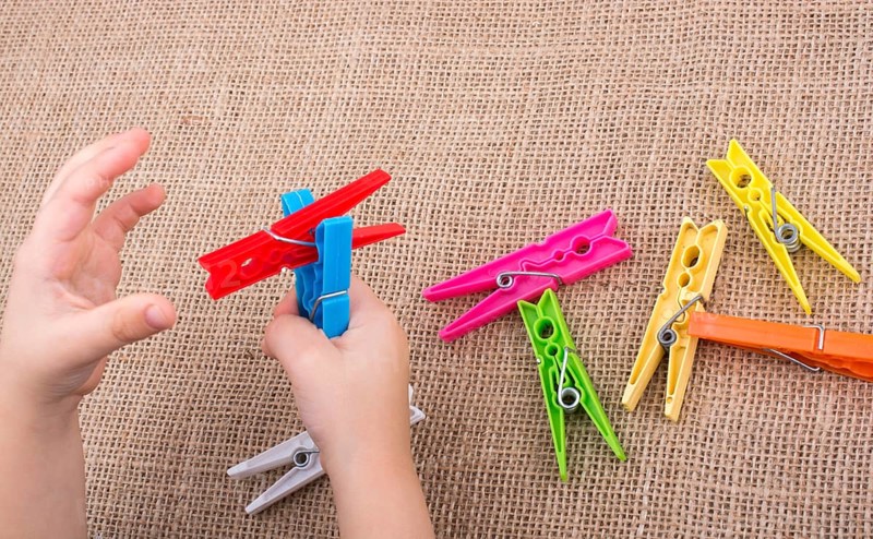 Color clothespin in hand on a linen canvas background