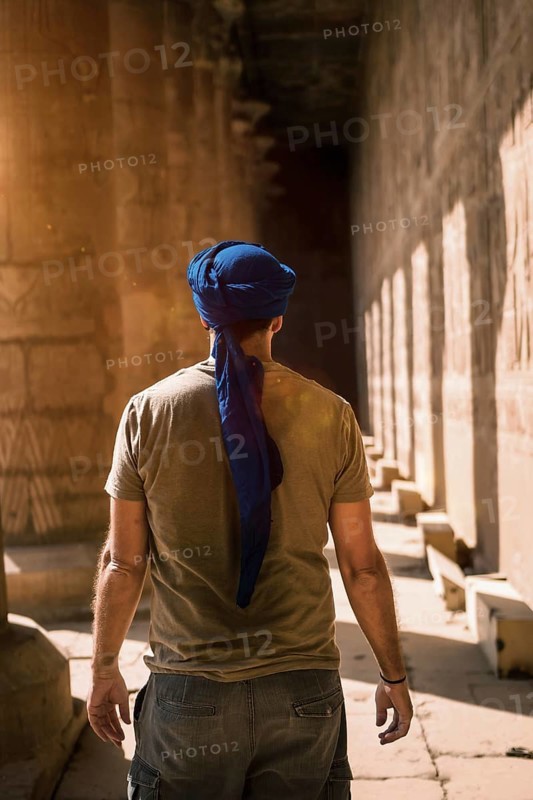 Young man in blue turban walking on the columns of the Edfu Temple near the city of Aswan. Egypt