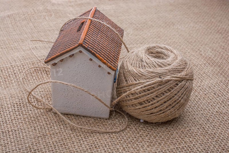 Thread wrapped around a model house on a brown background