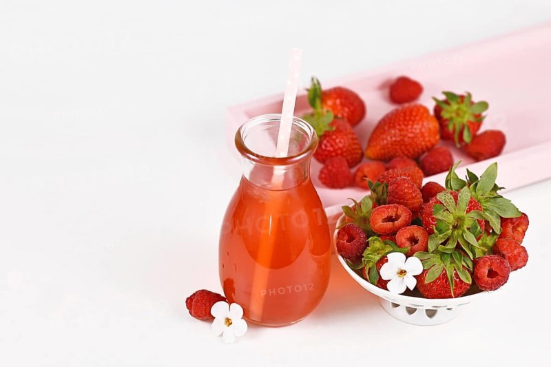 Red strawberry and raspberry fruit lemonade in jar surrounded by berries