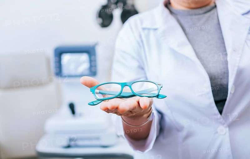 Optometrist hands showing a glasses. Oculist giving glasses in palm hand. Eyeglasses and visual health concept