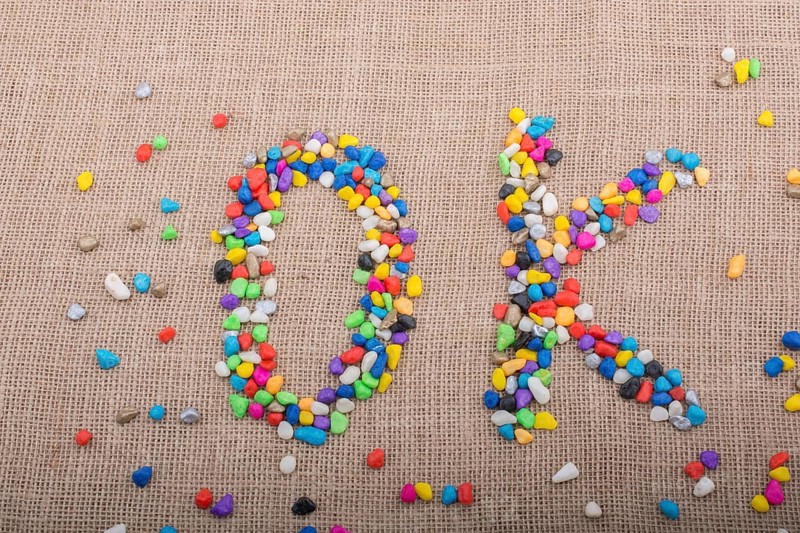 Colorful pebbles form the word OK on canvas ground