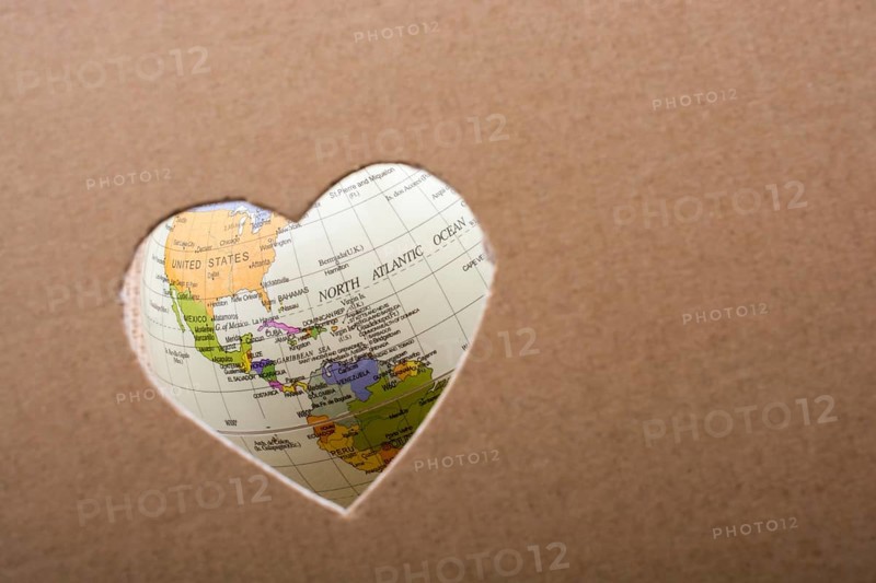 Globe seen through the heart shape hole on paper
