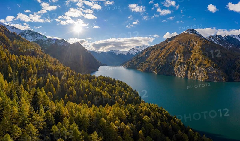 Aerial view in front of sunset over the autumnal forest at Lago di Luzzone in Valle di Blenio