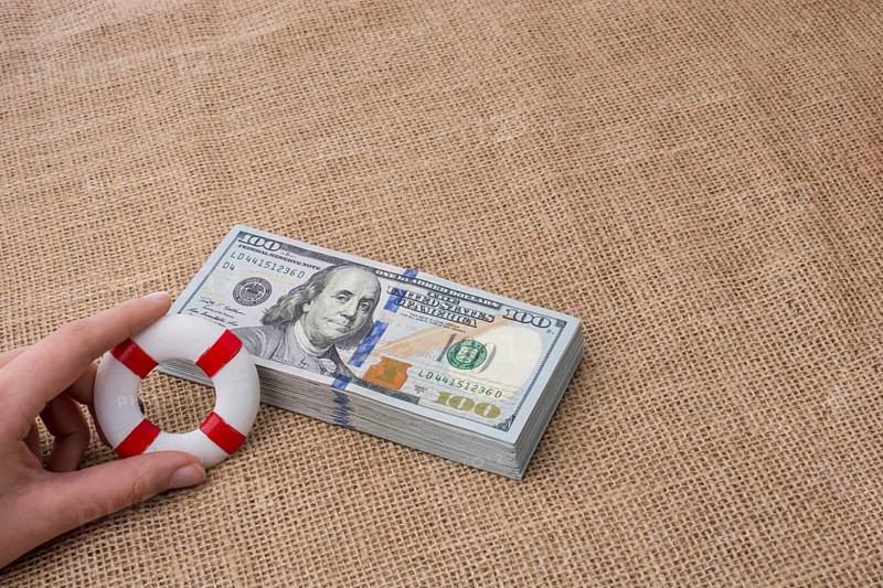 Life preserver in hand over the banknote bundle of US dollar