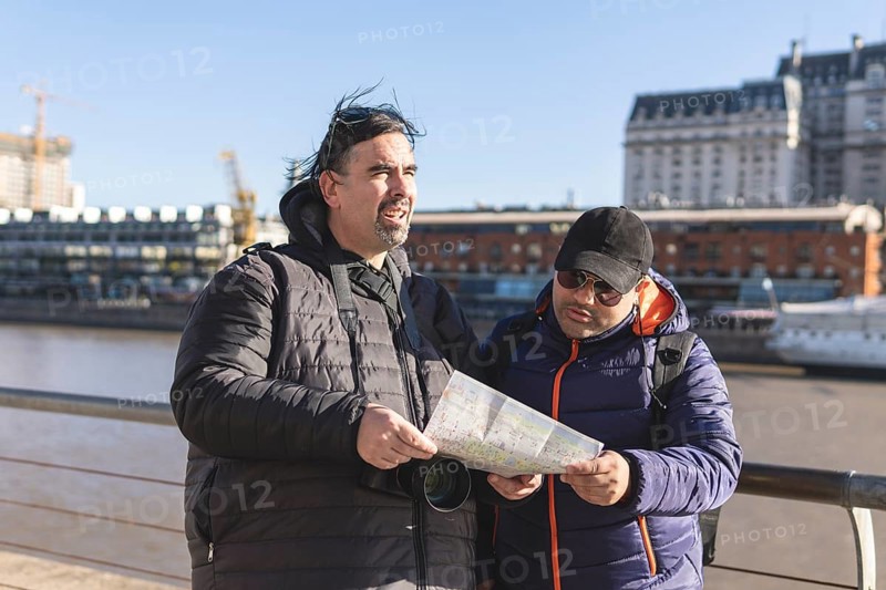 Couple of friends consulting the map while exploring Puerto Madero