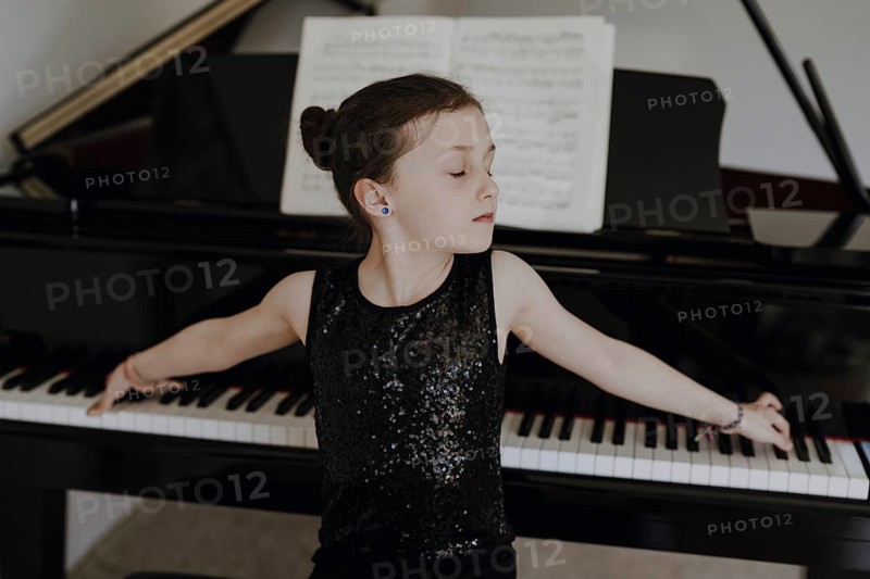 Elegant girl sits at the concert grand and plays the piano