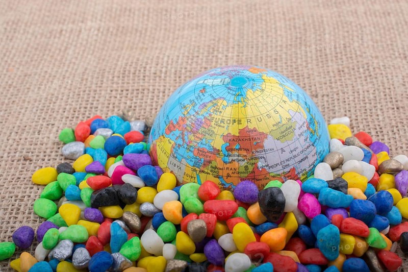 Model globe placed amid colorful pebbles