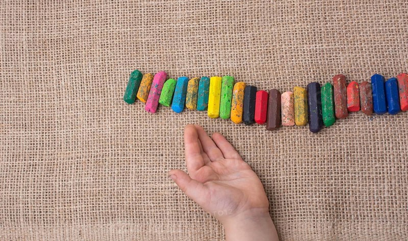 Toddlers hand putting crayons in line on canvas