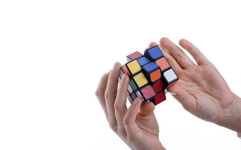Child holding a Rubik's cube in hand on a white background