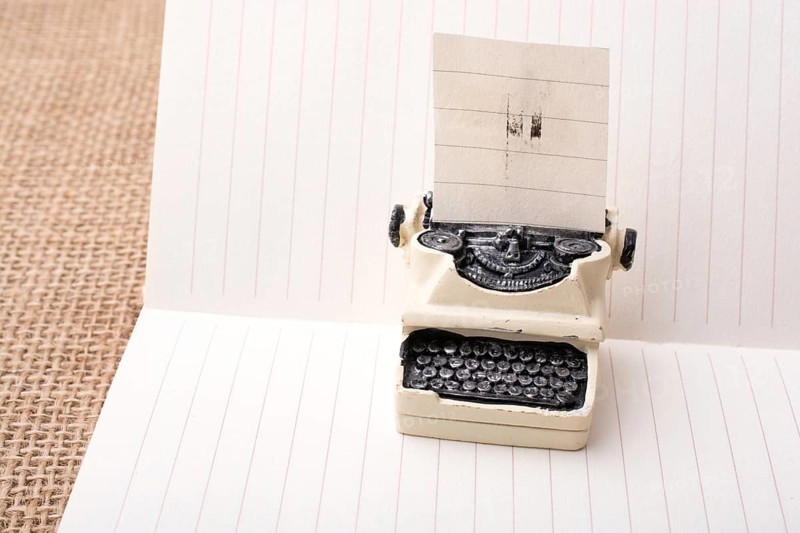 Retro syled tiny typewriter model on a paper background