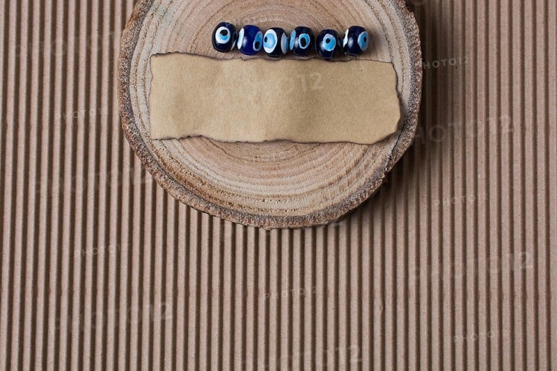 Evil eye beads and piece of burnt paper on wood log