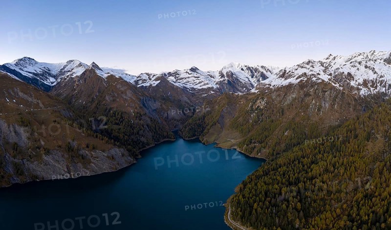Aerial view over Lago di Luzzone with the snow-covered mountain peaks in the background