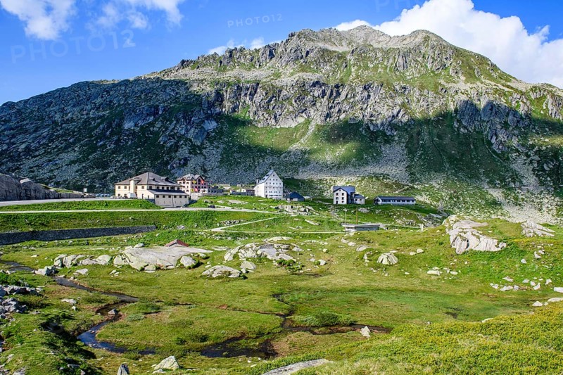 Panoramic view onto the high plateau at the top of the pass 2091 metres high Gotthard Pass with historic buildings in the middle historic hotel accommodation Ospizio San Gottardo Saint Gotthard Hospice with historic buildings from year 1237 13th century