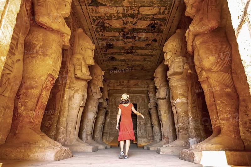 A young woman in a red dress at the Abu Simbel Temple next to the sculptures