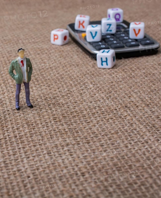Colorful letter cubes and a calculator beside a figurine