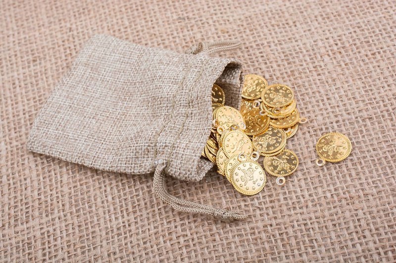 Fake gold coins out of a little sack on canvas