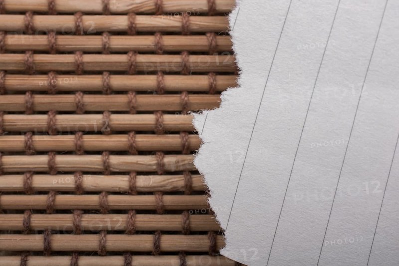 Piece of torn paper on a straw background