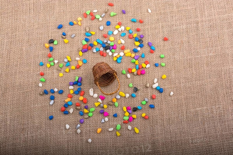 Basket and spilled pebbles on canvas background