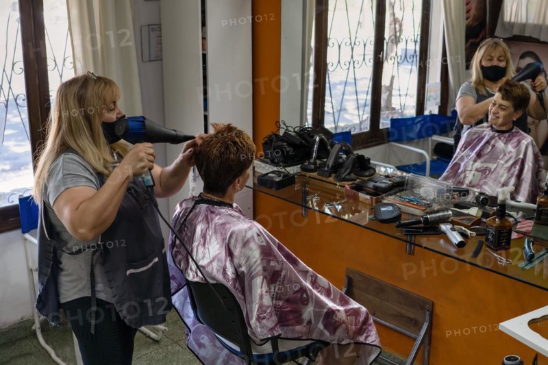 Latin hairdresser. Hairdresser blow-dries his client's hair. General shot