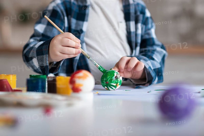 Close up little boy painting eggs easter