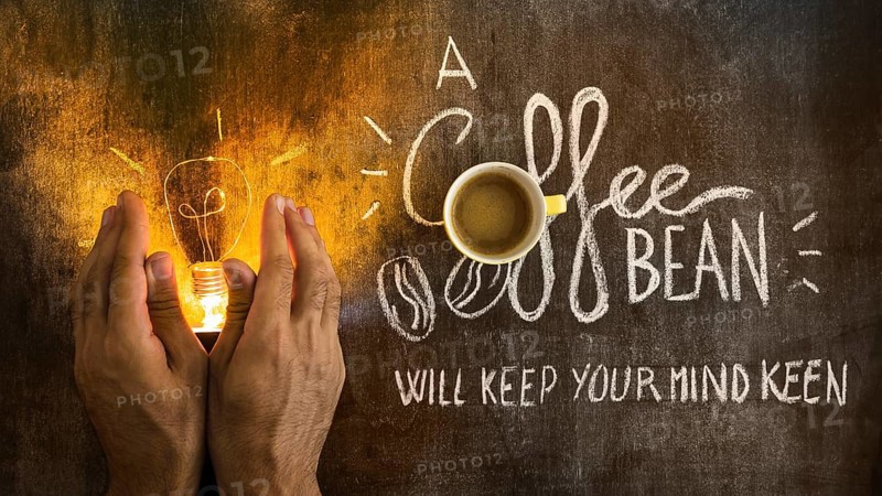 Hand covering illuminated light bulb with text chalkboard