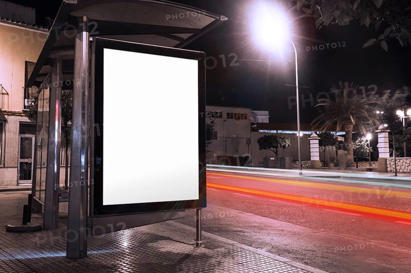 Blank advertisement bus shelter with blurred traffic lights night