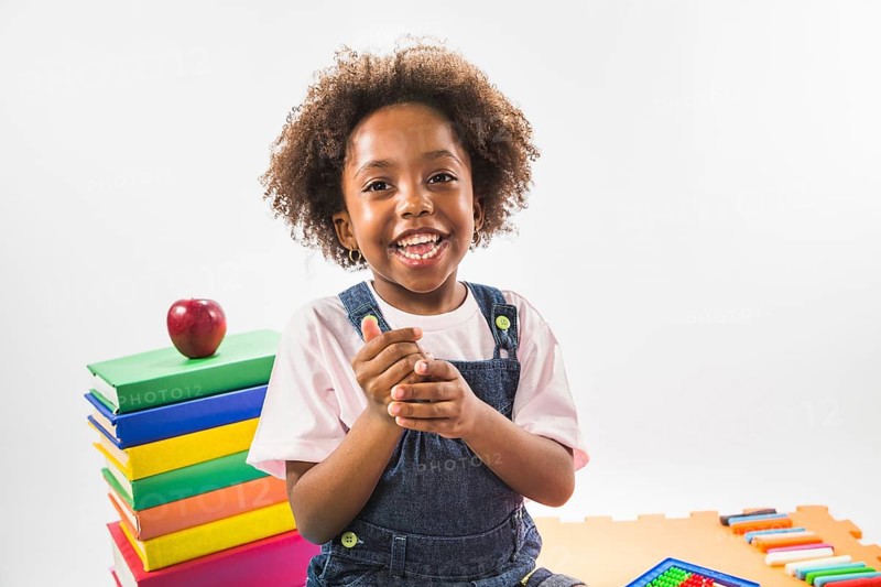 Kid sitting books smiling studio