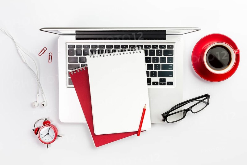 Overhead view office supplies laptop coffee cup alarm clock spectacles white desk